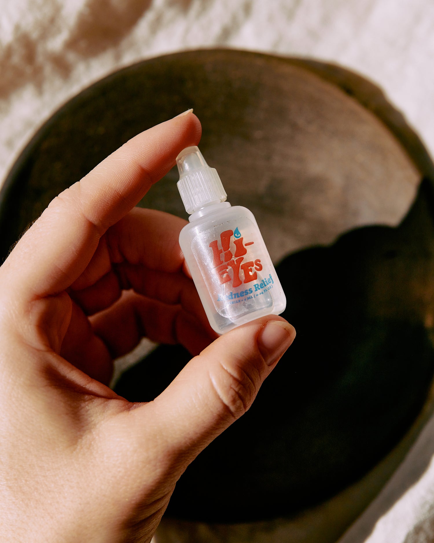 a person holding a bottle of hi eyes drops